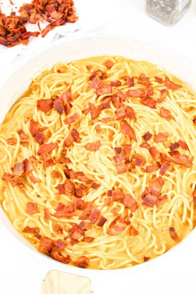 A bowl of creamy Pumpkin Carbonara topped with crispy bacon pieces.