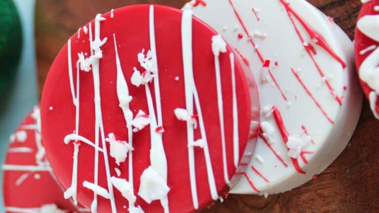 Two round, decorated cookies with red and white icing and sprinkles on a wooden surface.