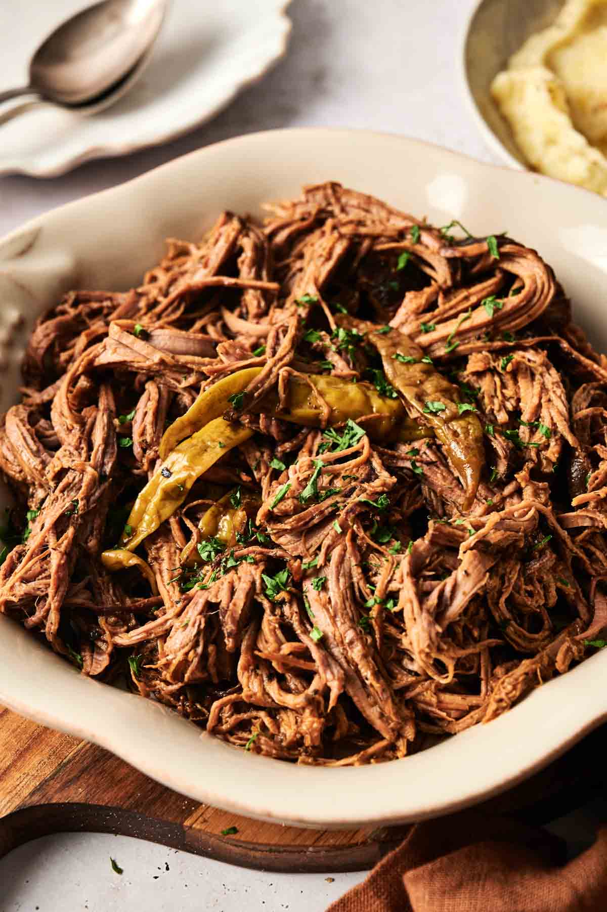 A dish of shredded beef, reminiscent of a classic Mississippi pot roast, garnished with parsley and bay leaves.