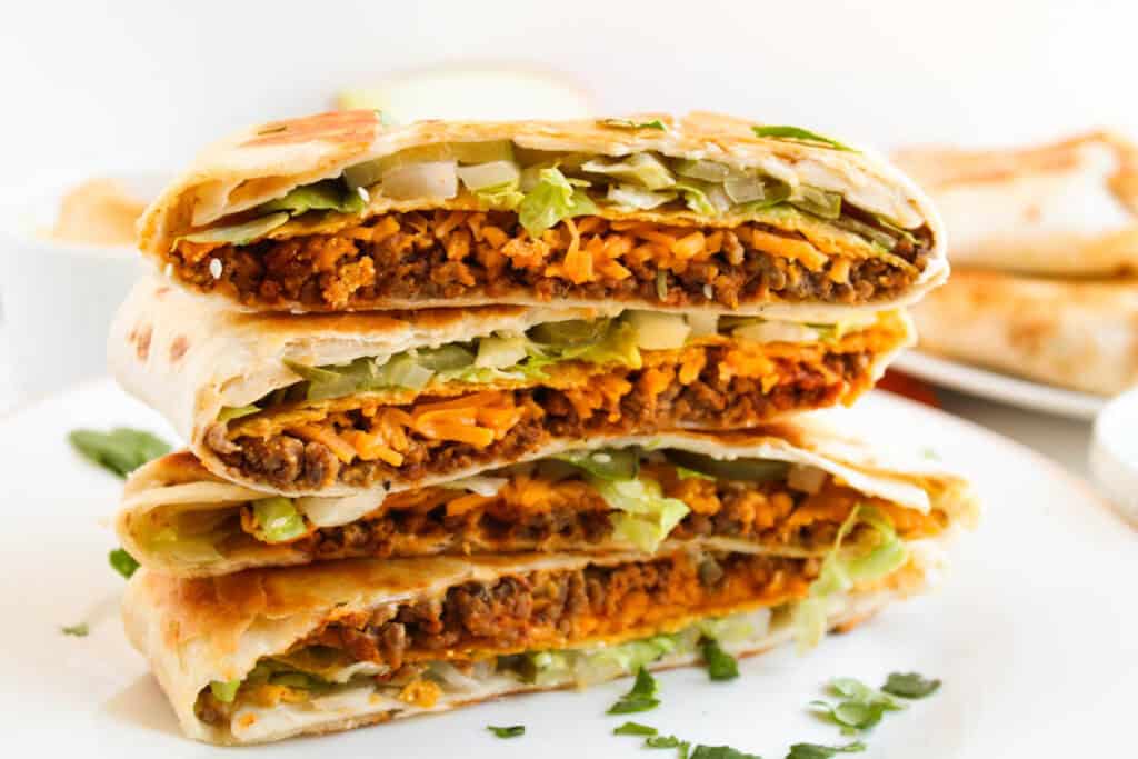 Big Mac crunchwrap stack sliced in half showing beef, cheese, lettuce, and pickles