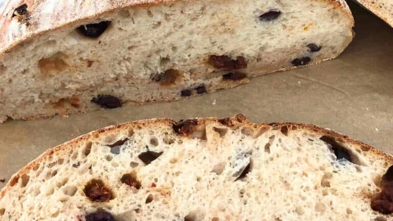 Close-up of sliced olive bread showing its texture and black olive pieces on a brown surface.