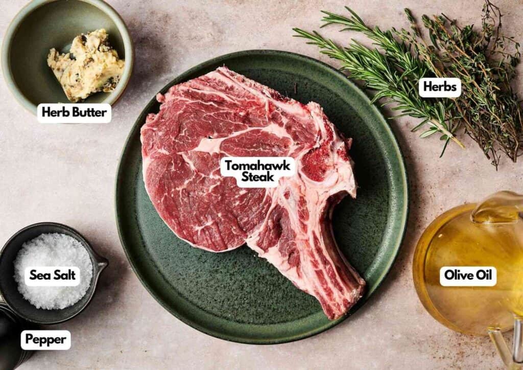 Tomahawk steak ingredients laid out on a light surface including a large bone-in tomahawk ribeye steak, herb butter, fresh rosemary and thyme, olive oil, sea salt, and pepper