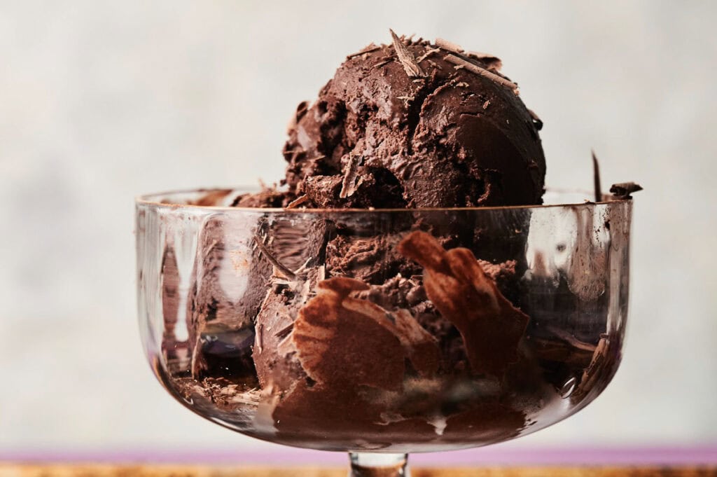 A glass bowl filled with rich chocolate ice cream, topped with delicate chocolate shavings.