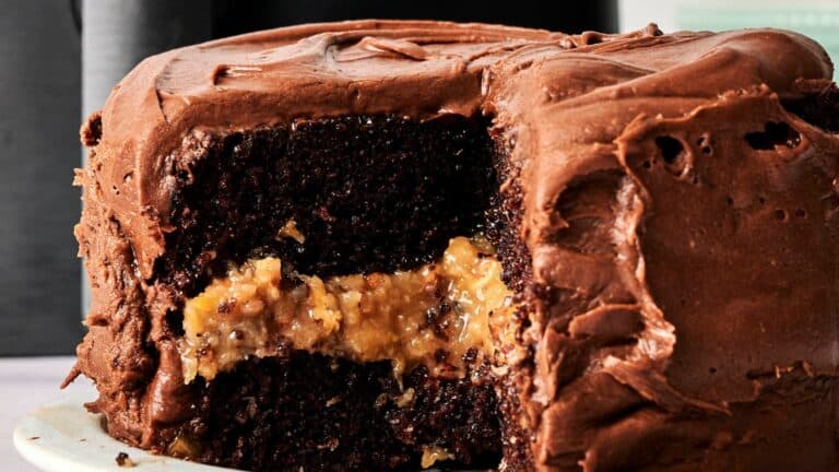 A sliced chocolate cake with chocolate frosting and a layer of coconut pecan filling in the middle.