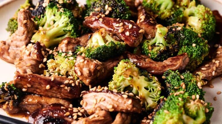 A close-up of a plate of beef and broccoli stir-fry topped with sesame seeds.