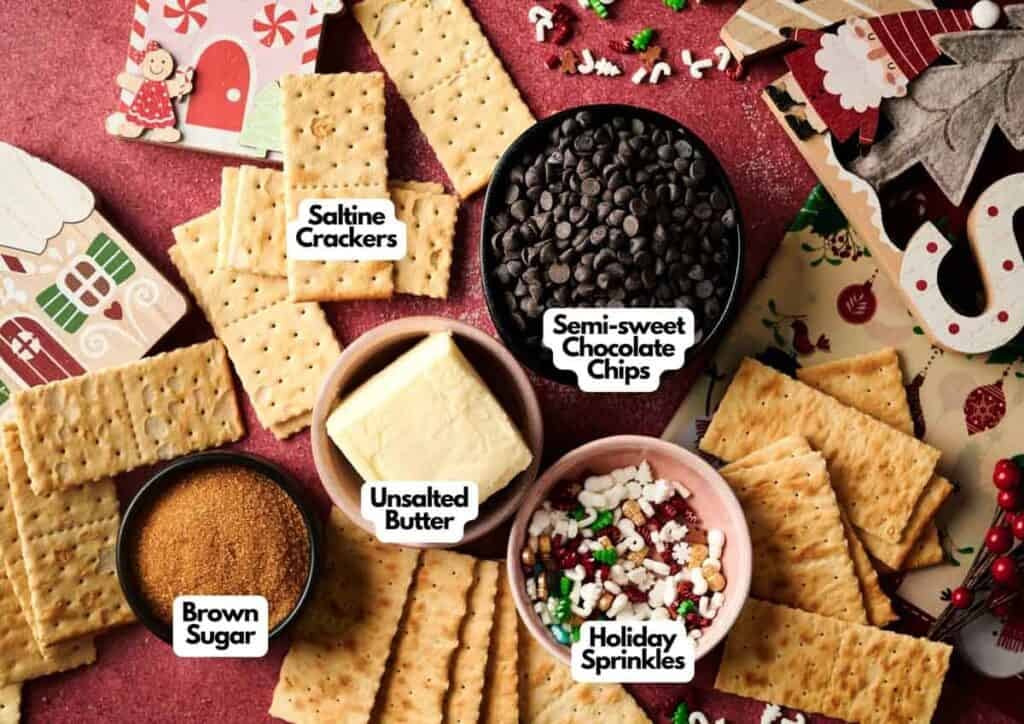 Christmas Crack made with saltine crackers, brown sugar, unsalted butter, semi-sweet chocolate chips, and holiday sprinkles arranged on a festive red background.