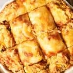 A close-up of an Air Fryer Cornbread Casserole with a golden, cheesy crust cut into square pieces, revealing a textured, cornbread-like interior.