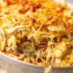 A close-up of a spoonful of cheesy baked pasta with shredded chicken and a golden, crispy topping from a savory Chicken Bacon Ranch Casserole.