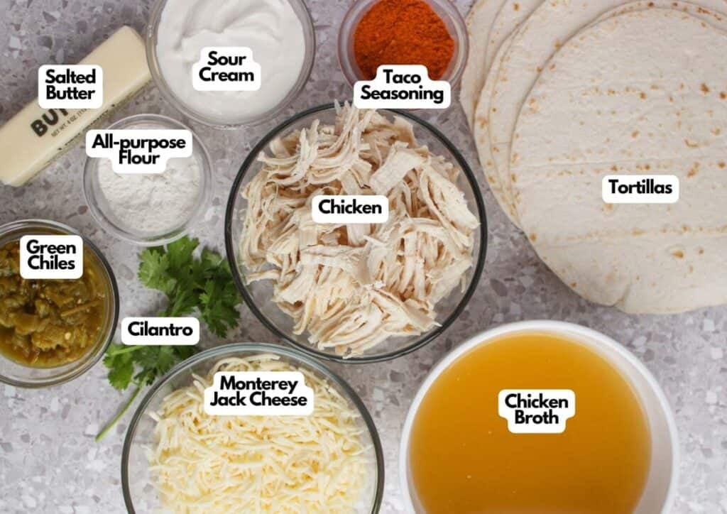 Various ingredients for making White Chicken Enchiladas, including shredded chicken, tortillas, cheese, green chiles, cilantro, sour cream, flour, butter, taco seasoning, and chicken broth.