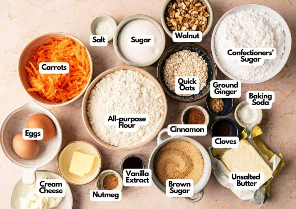 Assorted baking ingredients in bowls labeled as carrots, eggs, cream cheese, nutmeg, and more&mdash;everything you need to bake delicious Carrot Cake Cookies bursting with warm spices, oats, walnuts, and a hint of vanilla.