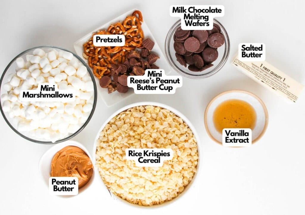 Top-down view of Chocolate Peanut Butter Rice Krispies ingredients in bowls: mini marshmallows, pretzels, milk chocolate melting wafers, salted butter, vanilla extract, rice krispies cereal, peanut butter cups, and peanut butter.