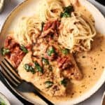 Plate of creamy Air Fryer Marry Me Chicken with sun-dried tomatoes, spinach, and spaghetti pasta, garnished with cracked black pepper.