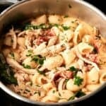 A pot of pasta with shredded chicken, spinach, tomatoes, and grated cheese, garnished with chopped parsley—perfect alongside a bowl of Air Fryer Marry Me Chicken Soup for a comforting meal.