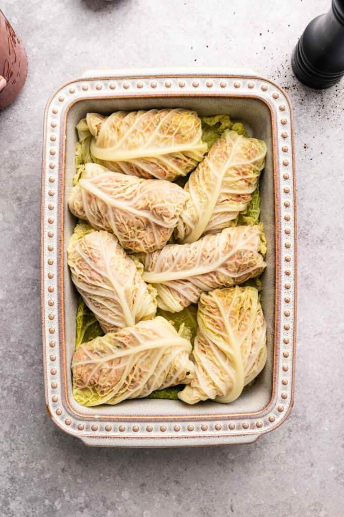 Rolled cabbage rolls arranged seam side down in a baking dish