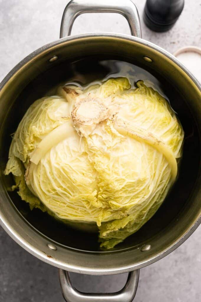 Overhead view of a cabbage head simmering in water for cabbage rolls