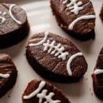 Football Shaped Brownies decorated with white icing to resemble footballs, arranged on a white plate.