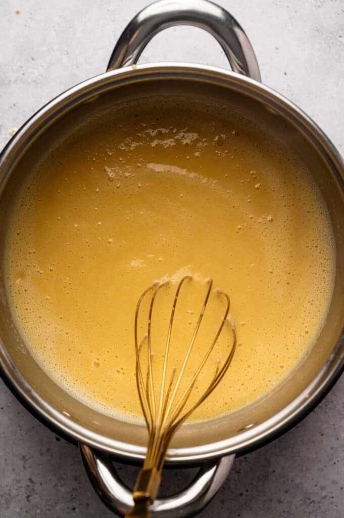 Overhead view of custard sauce being whisked smooth in a saucepan
