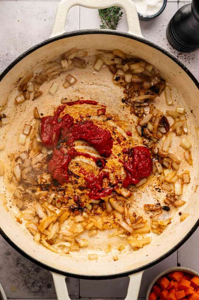 Overhead view of tomato paste cooking into saut&eacute;ed onions and garlic