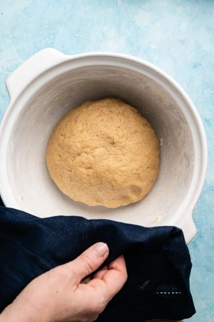 Overhead view of doubled sweet dough resting in a white bowl