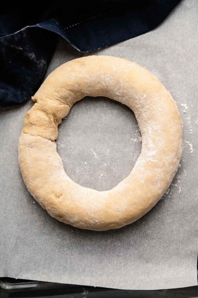Raw King Cake dough shaped into a ring on parchment paper