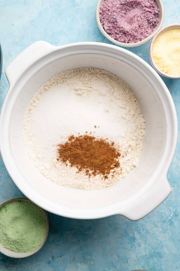 Flour, sugar, and cinnamon in a white mixing bowl before combining