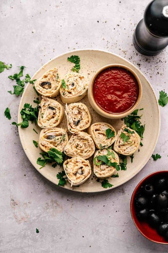 Mexican pinwheels served on a plate with salsa and cilantro