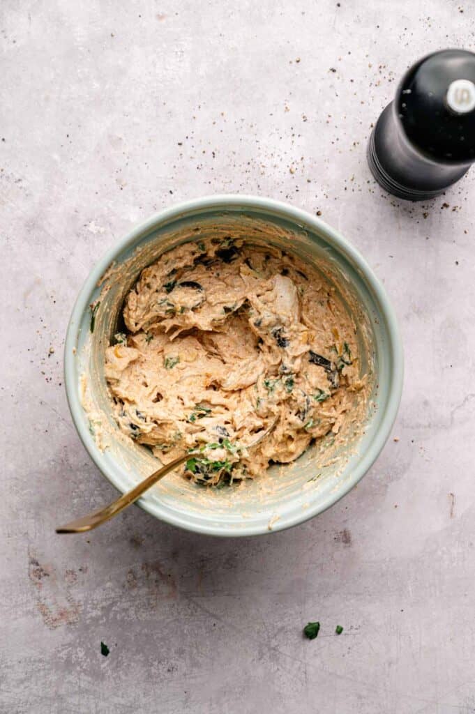 Creamy chicken pinwheel filling with sour cream, cheese, and olives in a mixing bowl
