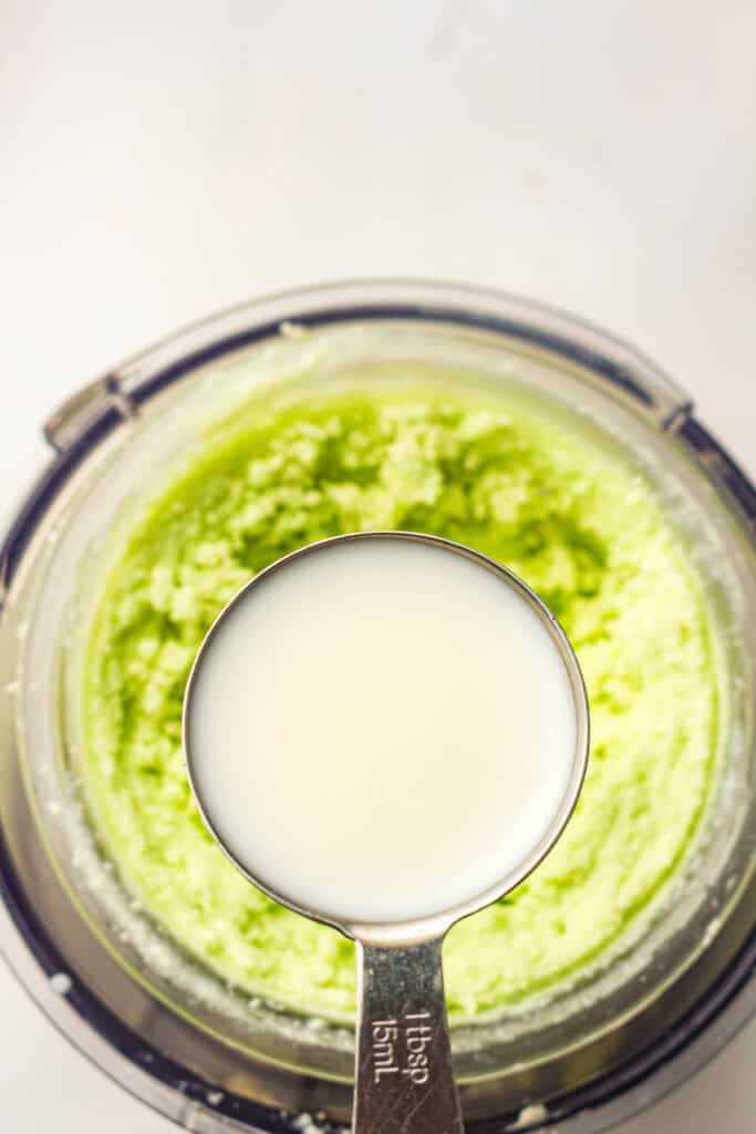 Milk being poured into churned mint ice cream to smooth the texture