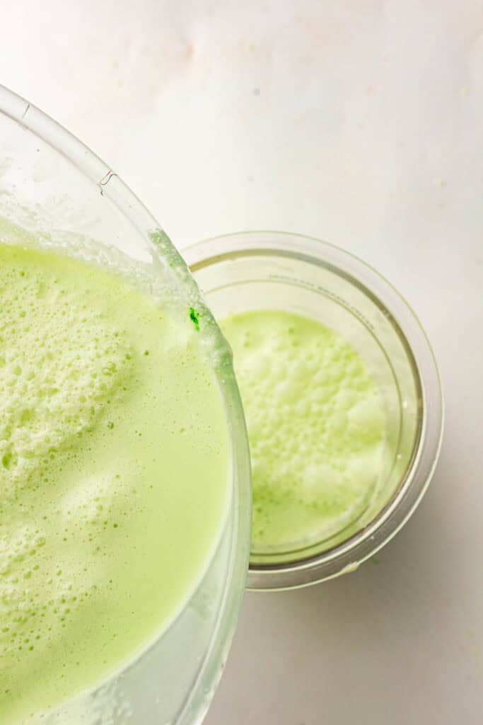 Green mint ice cream base being poured into a Ninja Creami pint container