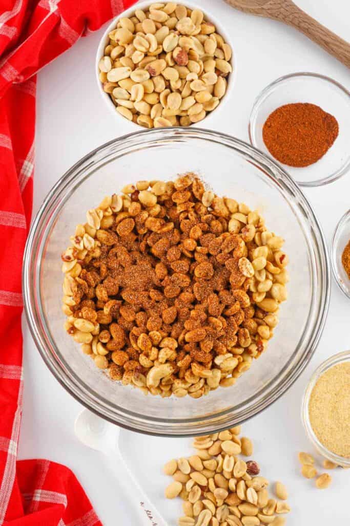 Peanuts tossed with chili powder and spices in a glass bowl
