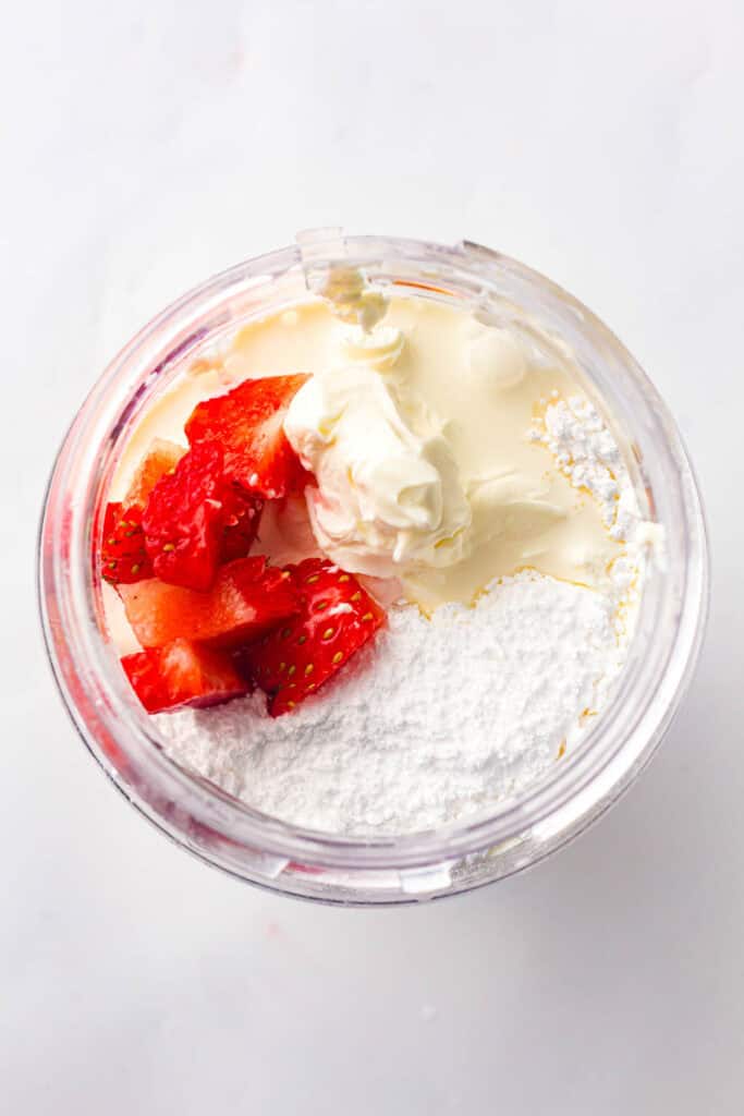 Strawberries, cream cheese, and sugar ready to blend for cheesecake ice cream