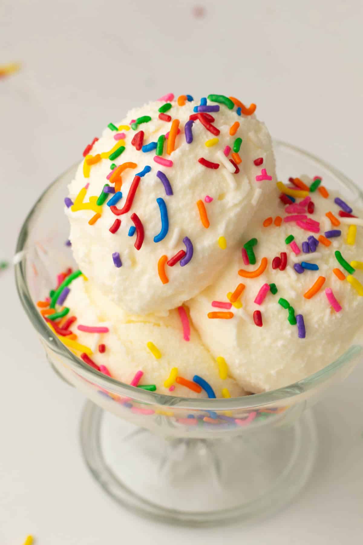 A glass bowl filled with scoops of Vanilla Ninja Creami Ice Cream, topped with colorful rainbow sprinkles.
