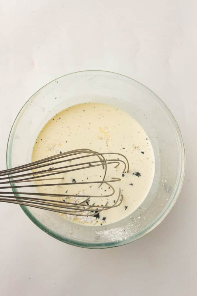Whisking vanilla bean ice cream base in a glass bowl
