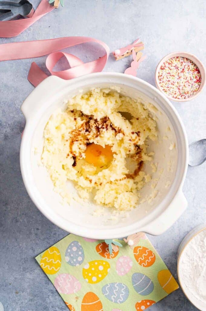 Egg and vanilla extract added to creamed butter and sugar in a bowl