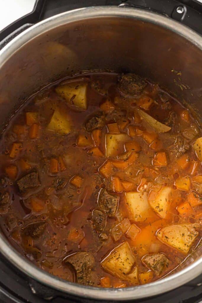Overhead view of beef stew ingredients combined with broth before pressure cooking