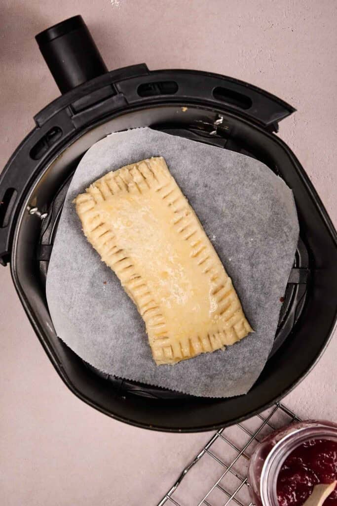 Unbaked sourdough pop tart with fork-crimped edges set in the air fryer basket