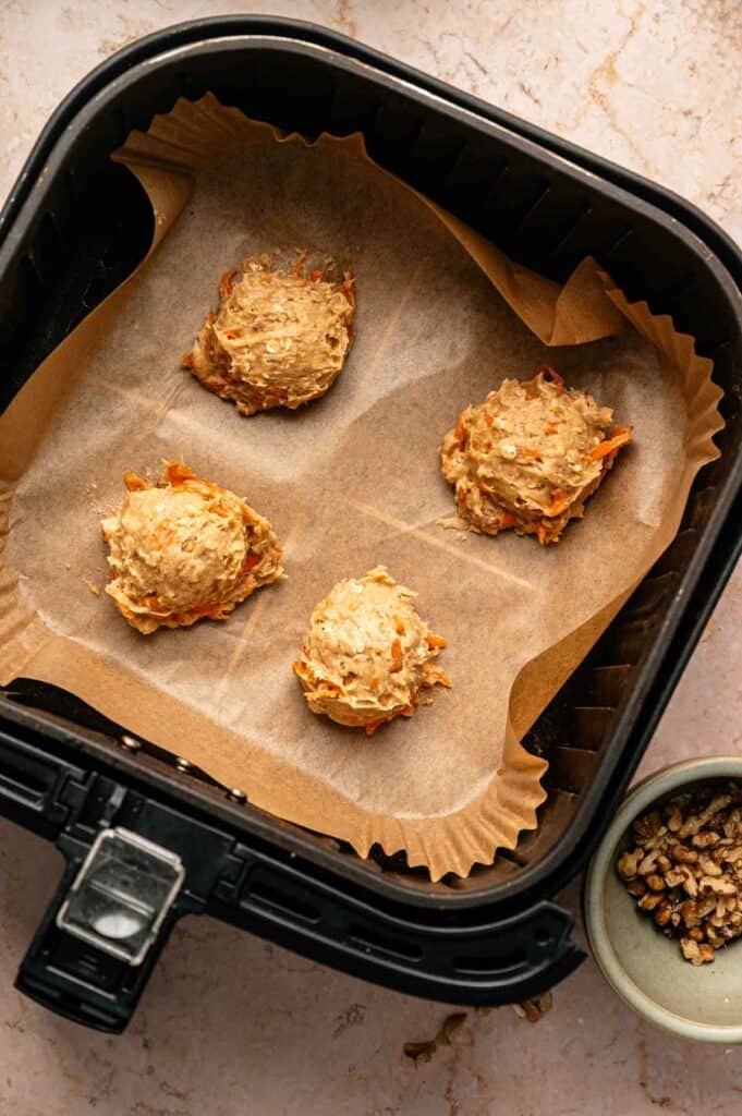 Unbaked carrot cake cookie dough balls spaced apart on parchment before air frying