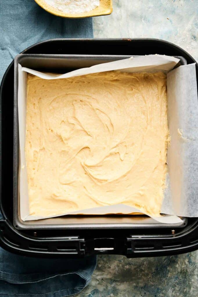 Unbaked lemon brownie batter smoothed into a lined baking pan, ready for the air fryer