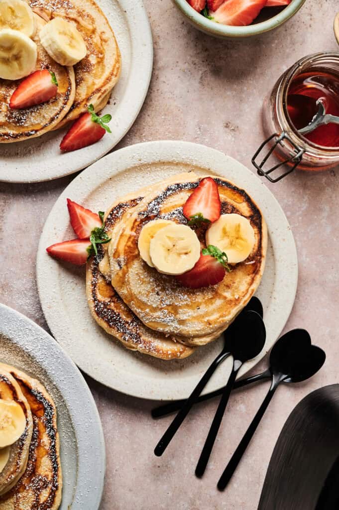 Stacked sourdough pancakes topped with banana and strawberries