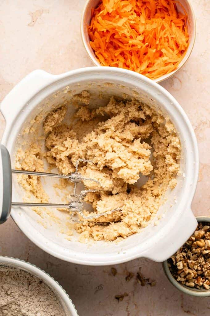 Creamy butter and sugar mixture in a white bowl with hand mixer beaters resting inside
