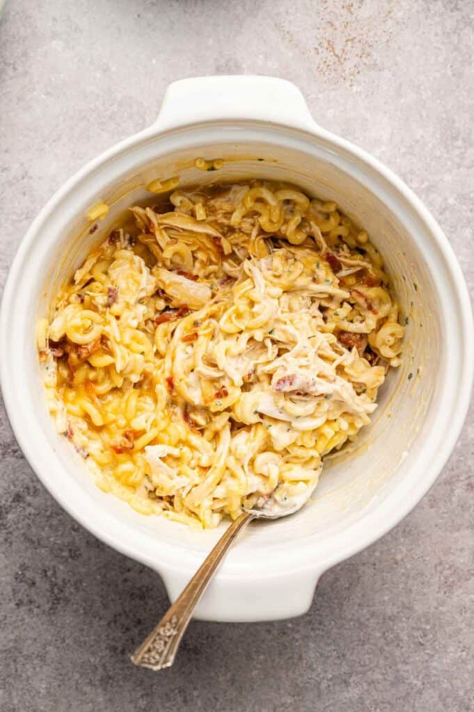 Creamy chicken bacon ranch casserole filling being stirred together with a spoon before baking