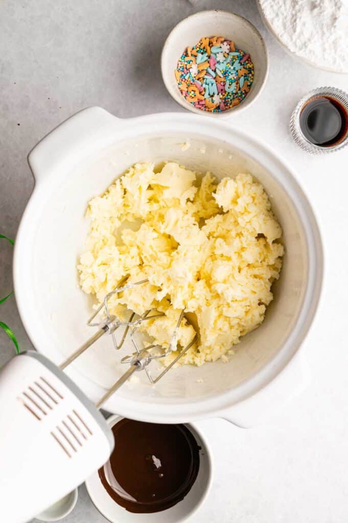 Overhead view of creamed butter for buttercream, surrounded by Easter decorating supplies