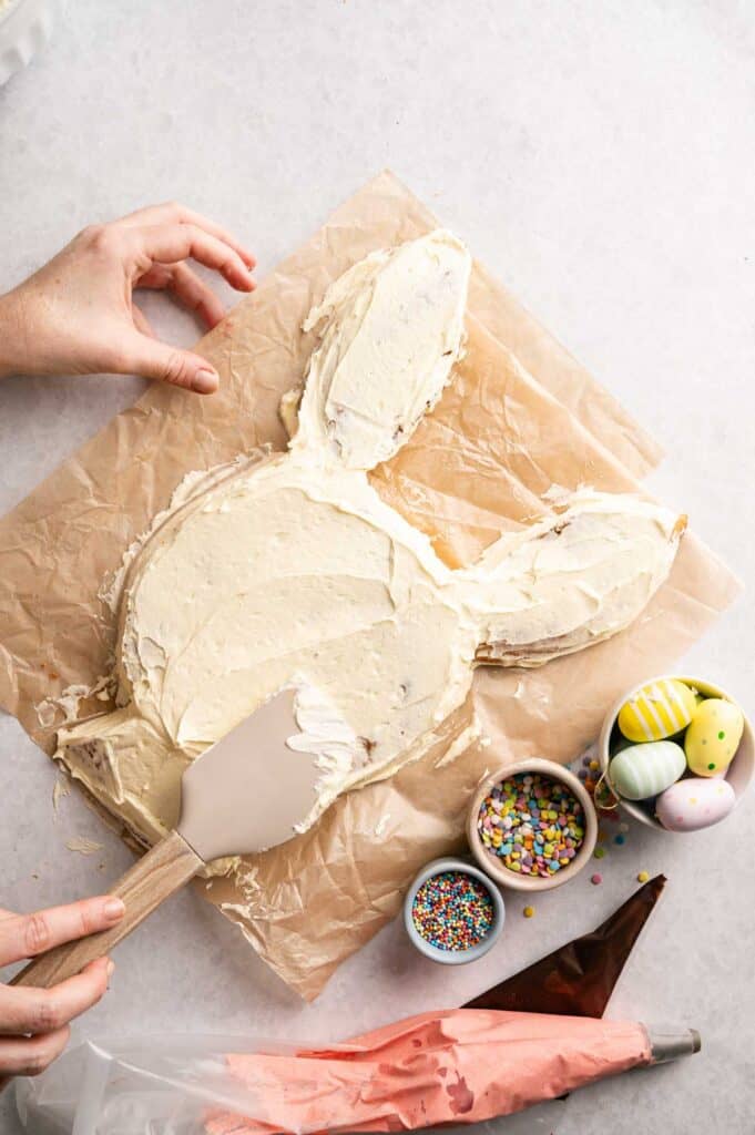 Overhead view of white buttercream being smoothed over the bunny cake shape