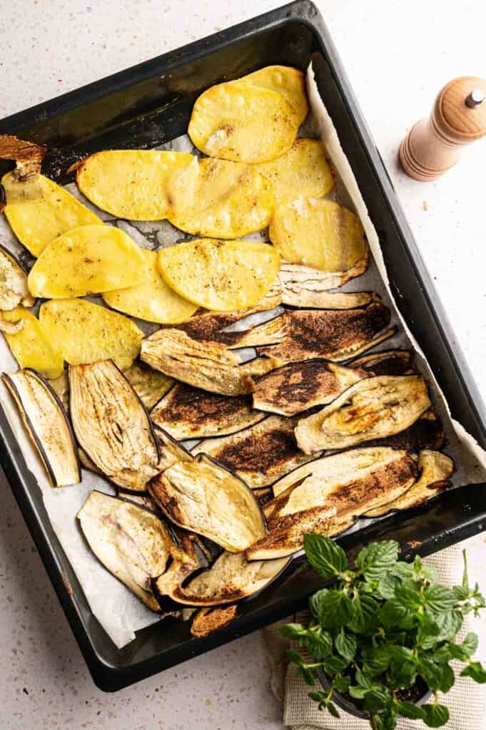Oven-roasted eggplant and potato slices ready for moussaka layers