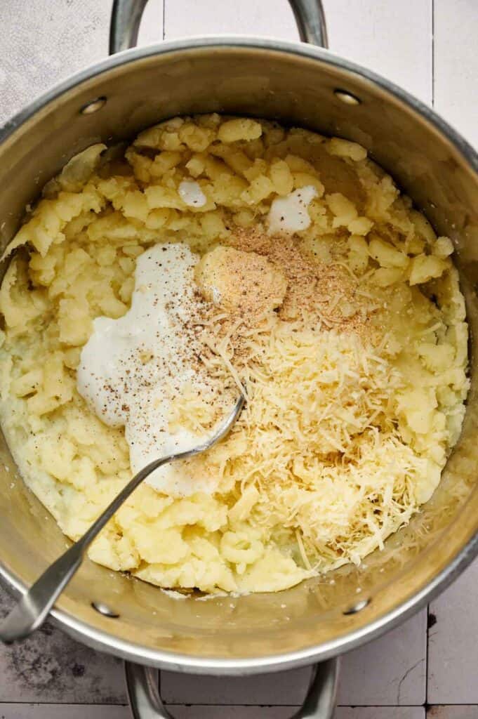 Mashed potatoes topped with sour cream and shredded cheese before mixing