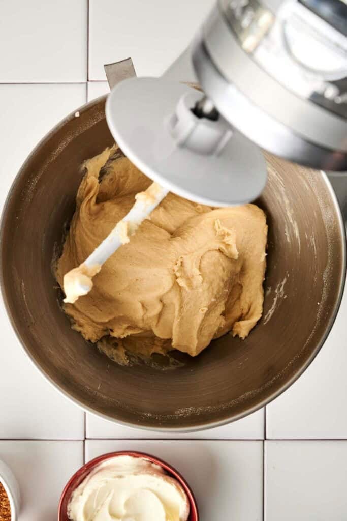 Sourdough cinnamon roll dough being kneaded in a stand mixer bowl with a dough hook attachment