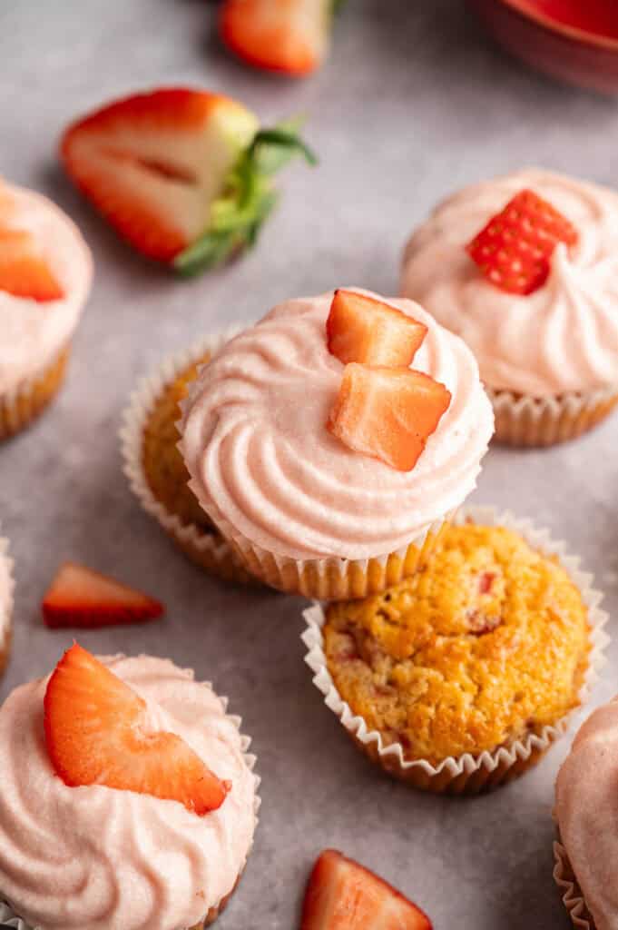 Strawberry cupcakes swirled with pink frosting and topped with fresh strawberry pieces