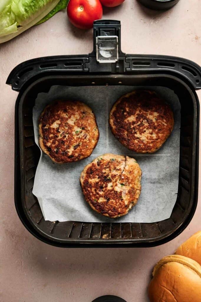 Crispy air fryer turkey burgers cooking in a basket, ready to serve.