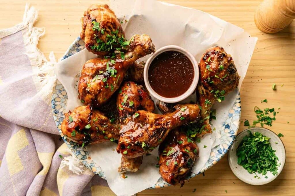 Delicious BBQ chicken drumsticks glazed with savory sauce, garnished with fresh herbs, perfect for backyard cookout.