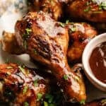 Delicious BBQ chicken drumsticks glazed with savory sauce, garnished with fresh herbs, perfect for backyard cookout.